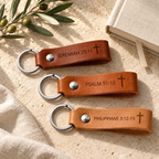 Three leather keychains in brown, cognac and tan, engraved with Bible references and crosses, each with silver hardware.