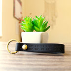 Custom full-grain leather coordinates keychain in cognac brown with laser engraved GPS location coordinates and compass symbol on front and personalized message on back with solid screw metal hardware ring.