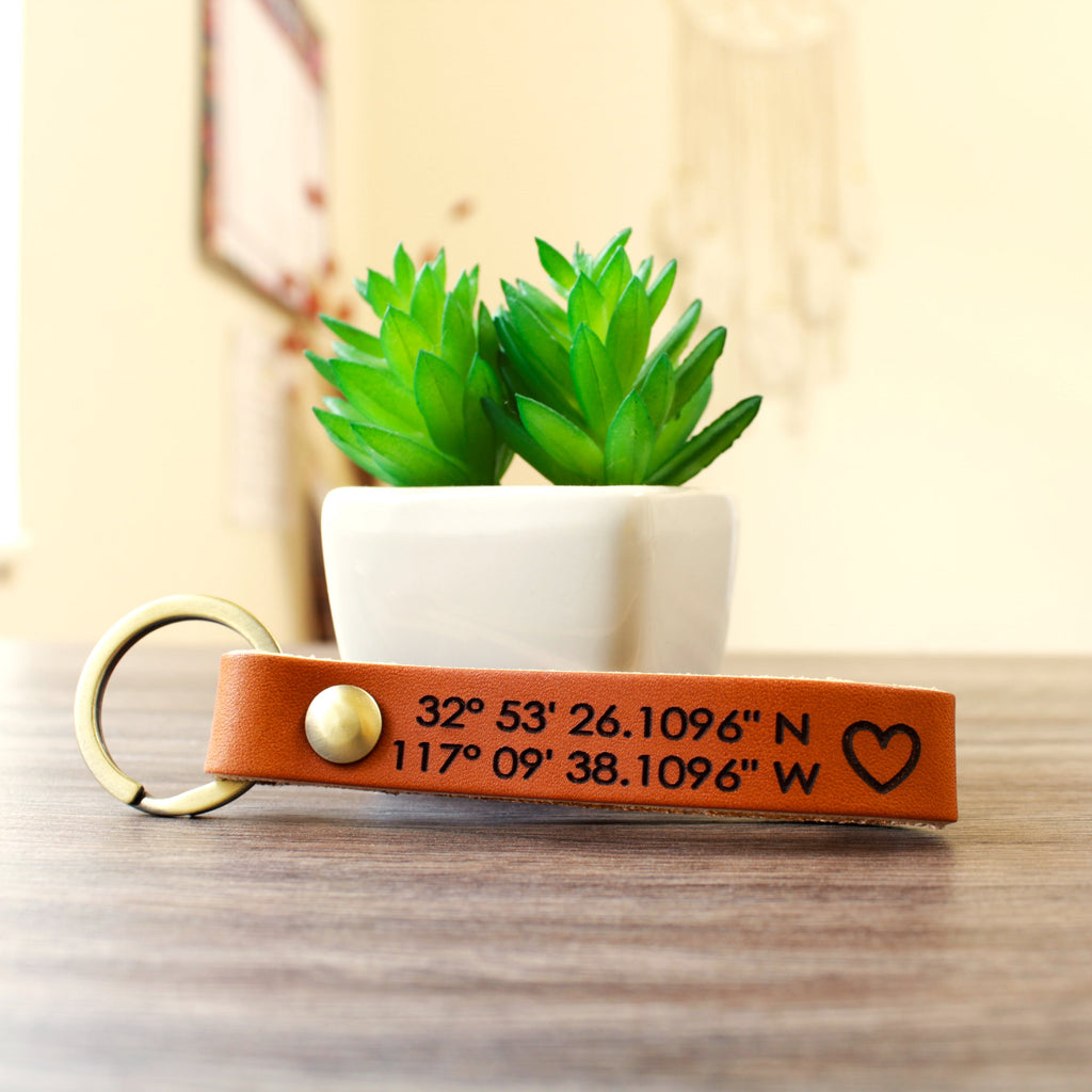 Custom full-grain leather coordinates keychain in cognac brown with laser engraved GPS location coordinates and compass symbol on front and personalized message on back with solid screw metal hardware ring.