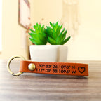 Custom full-grain leather coordinates keychain in cognac brown with laser engraved GPS location coordinates and compass symbol on front and personalized message on back with solid screw metal hardware ring.