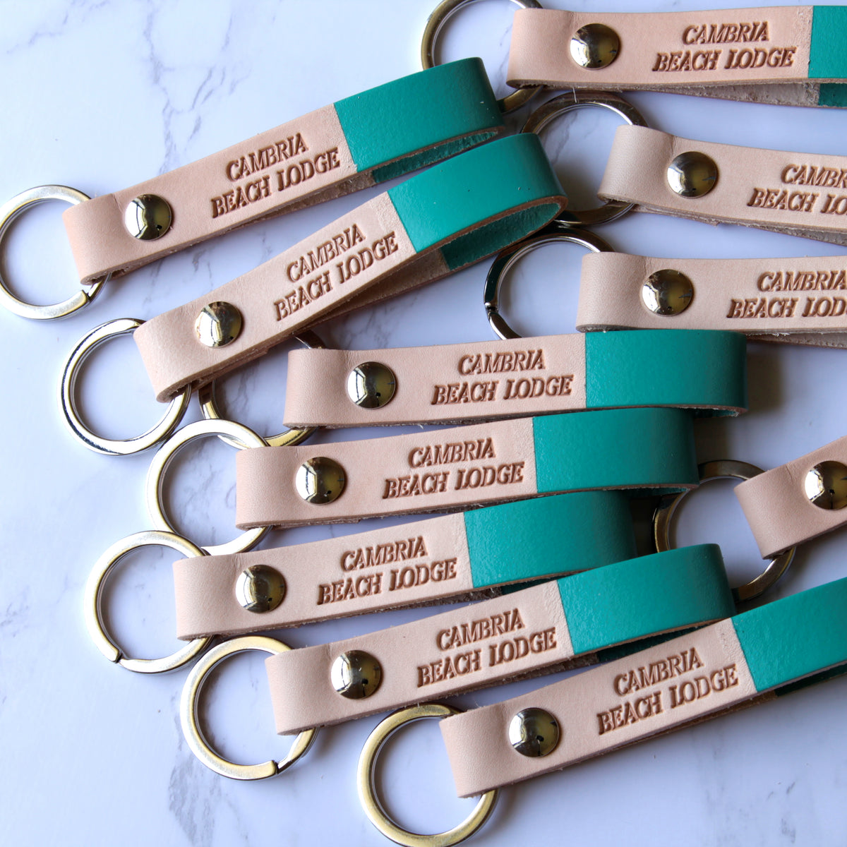 Multiple leather keychains with custom engraving, displayed on a light surface.