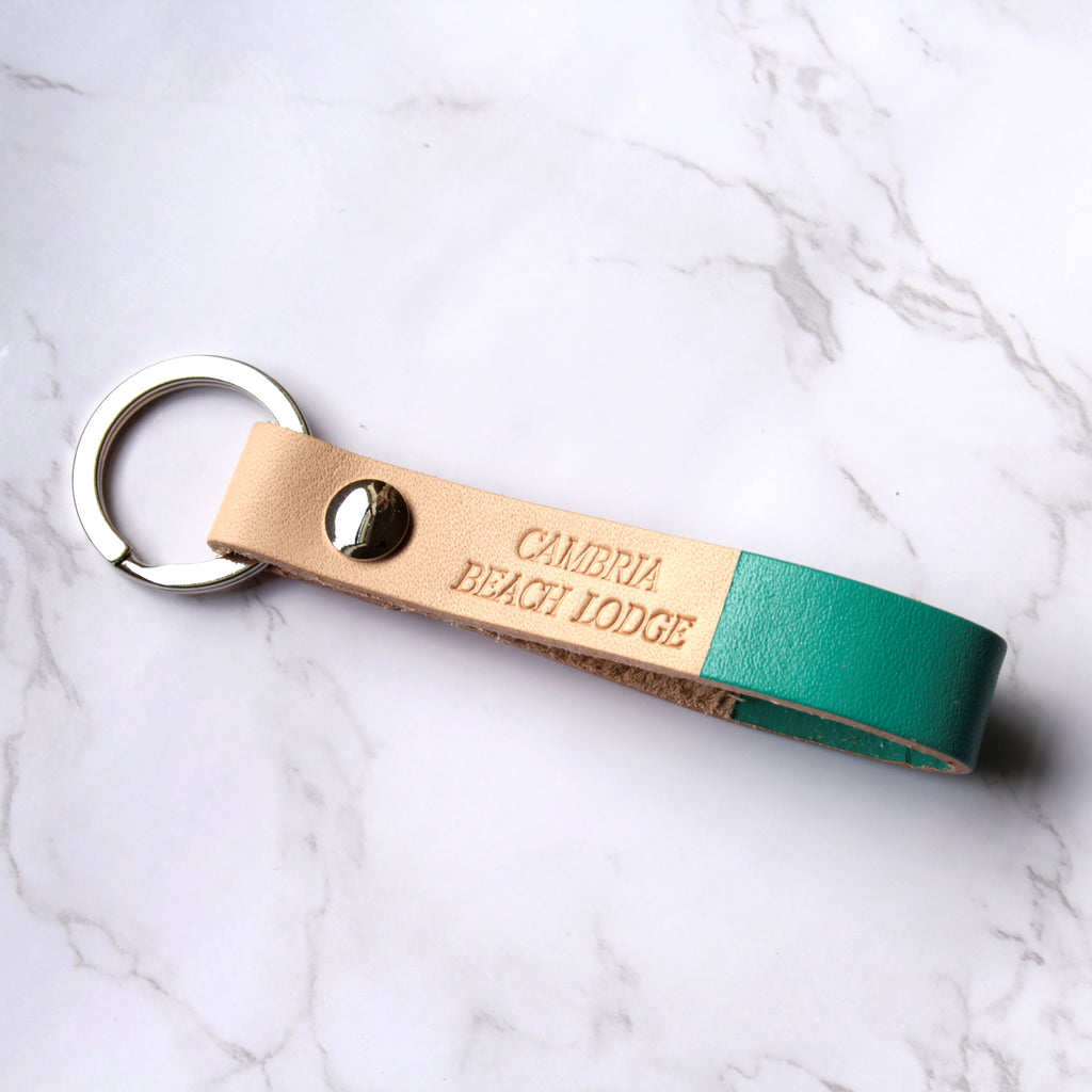 Multiple leather keychains with custom engraving, displayed on a light surface.