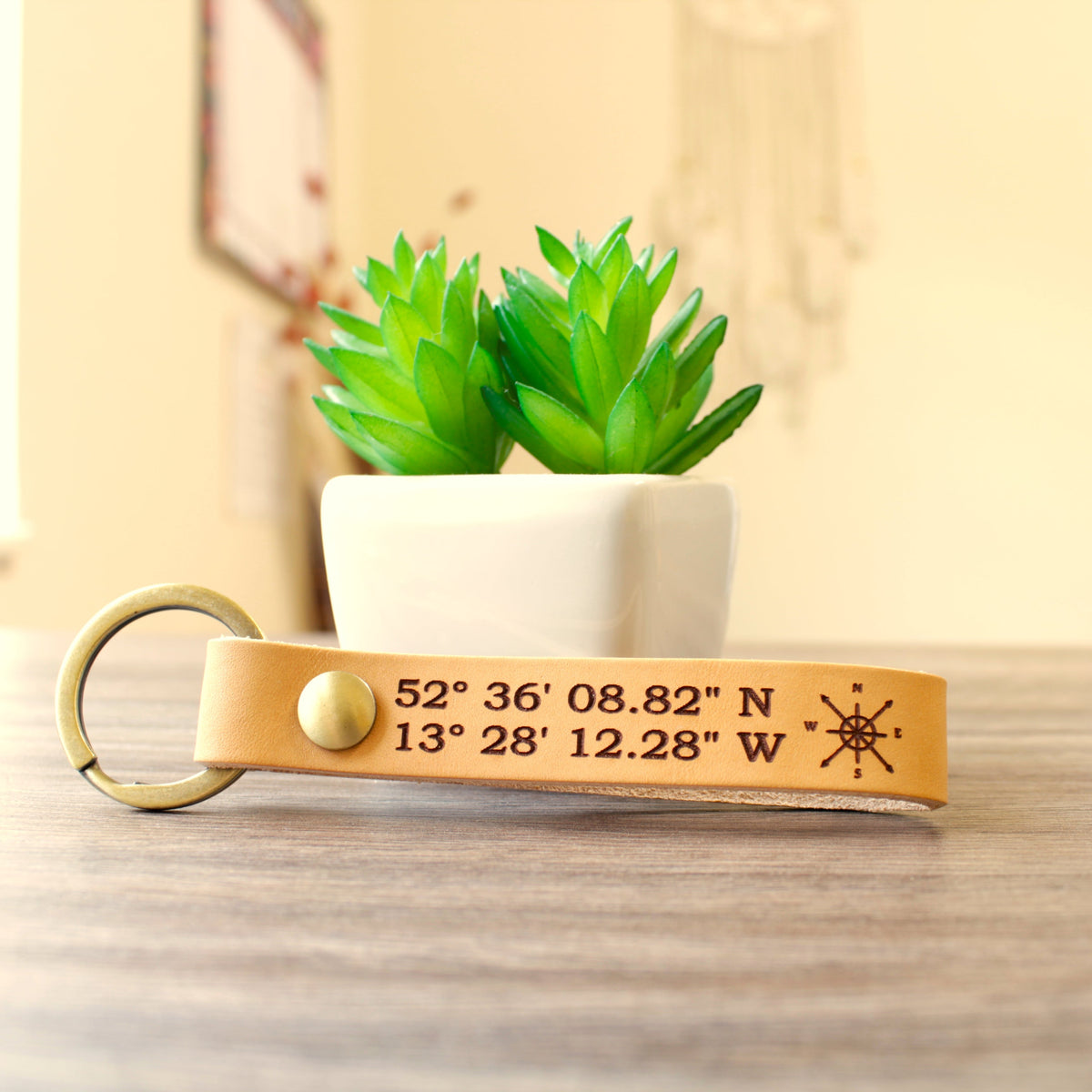 Custom full-grain leather coordinates keychain in cognac brown with laser engraved GPS location coordinates and compass symbol on front and personalized message on back with solid screw metal hardware ring.